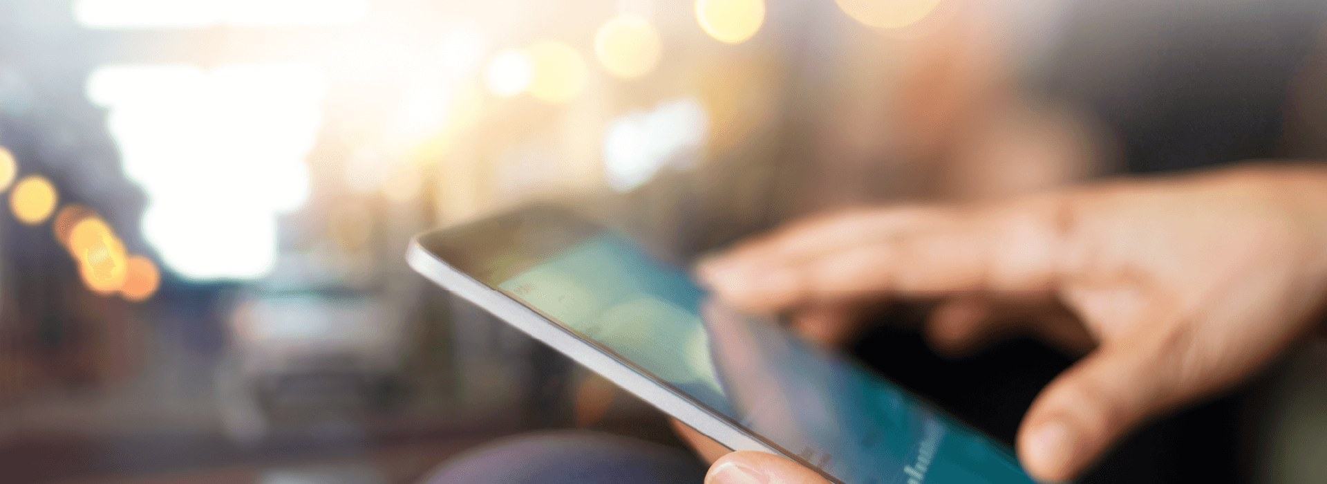 Kädet selaavat tablettia – Real Cleanin ajankohtaiset artikkelit yrityssiivouksesta